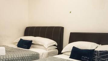 A hotel room with two beds, each with a pillow and a folded towel.