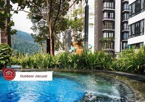 An outdoor jacuzzi surrounded by lush greenery and modern buildings. - MIDHILLS Prime Suites Genting Highlands (Genting Highlands)