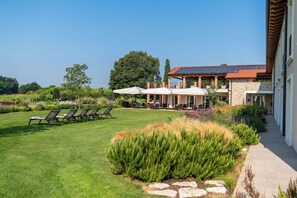 A well-maintained lawn with outdoor seating and a building with a red roof. - Relais Agriturismo Maria Vittoria (Sommacampagna)