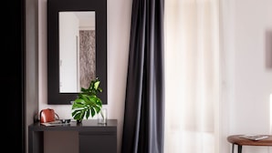 Een moderne kamer met een donker bureau, een grote spiegel, een kamerplant en een paar schoenen op de vloer.