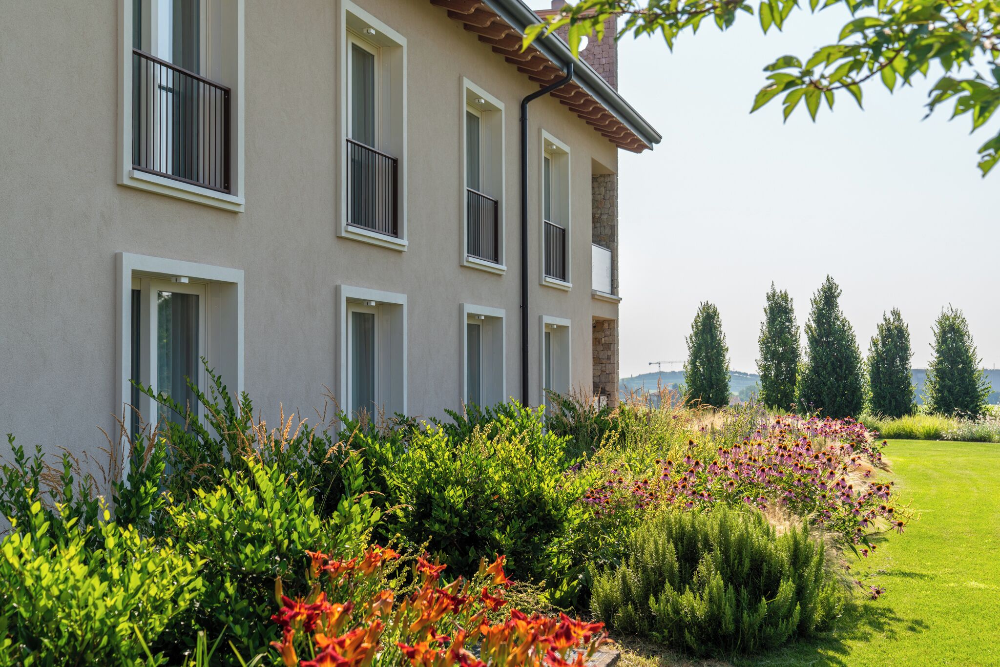 A multi-story building with balconies, surrounded by well-maintained gardens and a grassy lawn.