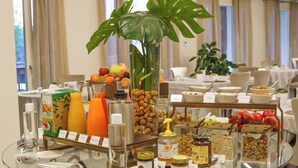 Een ontbijtbuffet met diverse gerechten, een glazen tafel en een plant.