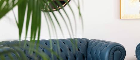 Un sofá azul, una mesa redonda con un cuenco y una planta en un salón moderno.