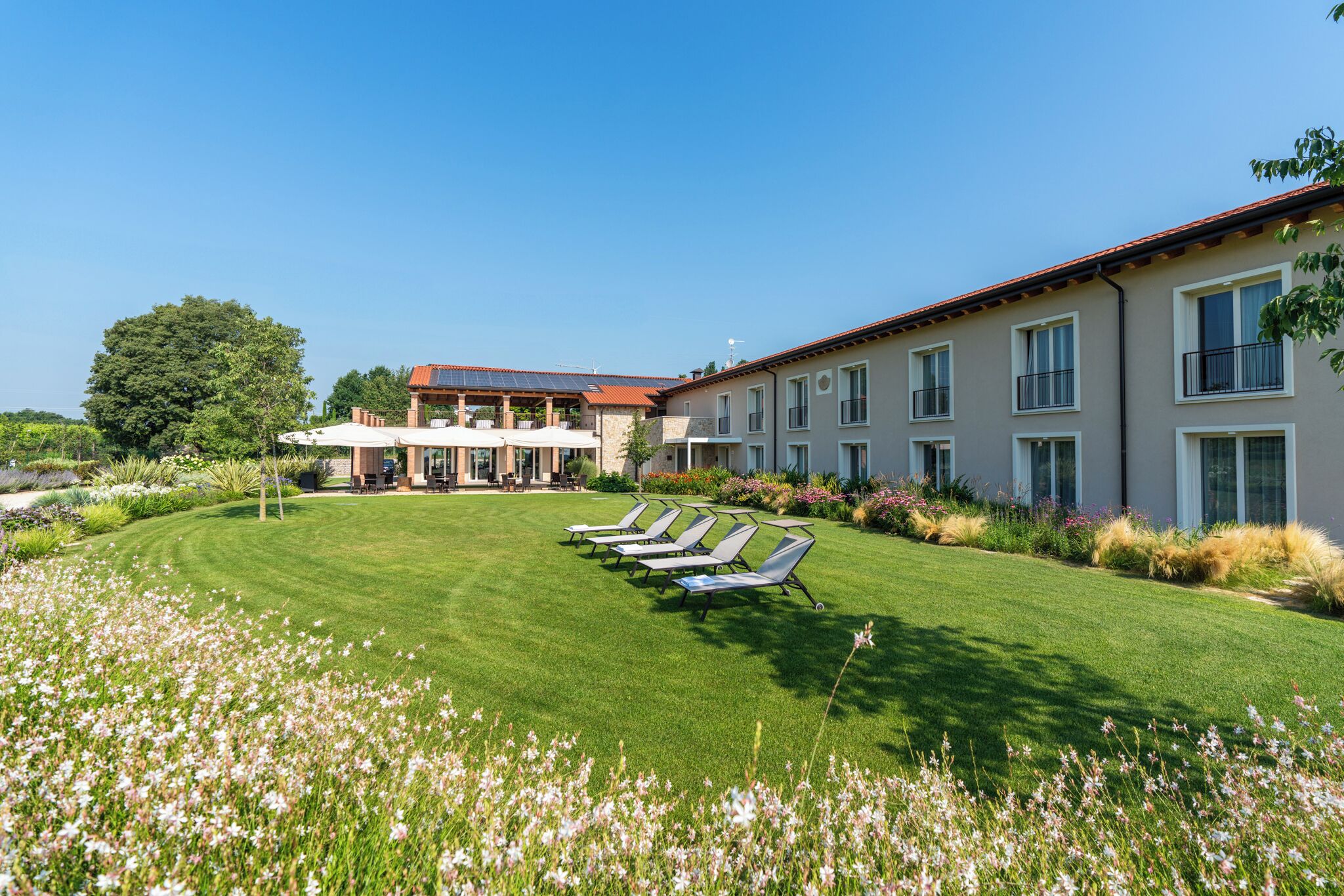 A hotel with a well-maintained lawn, outdoor seating area, and a large building with multiple windows.