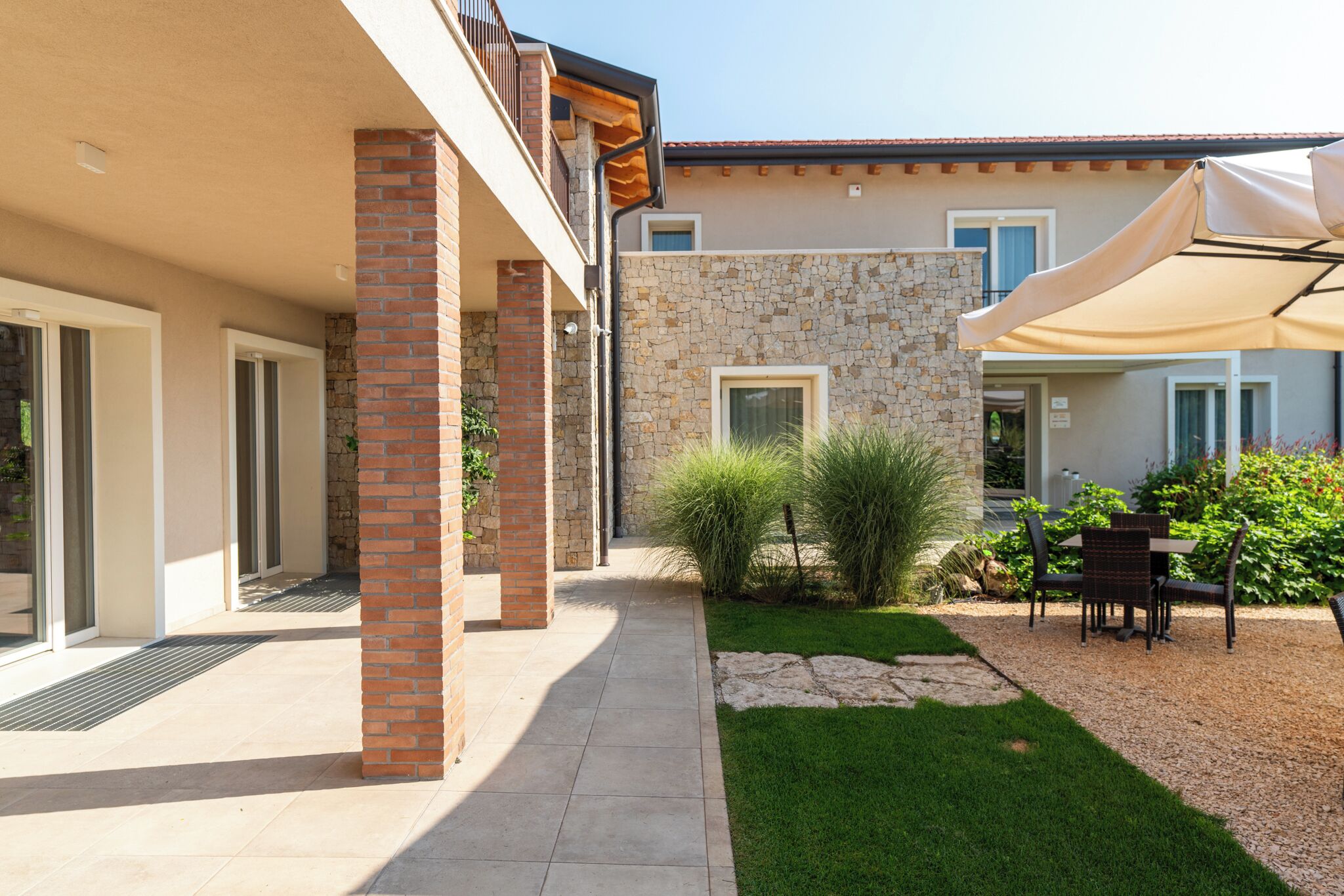 A courtyard with a patio, a stone wall, a door, and a table with chairs.
