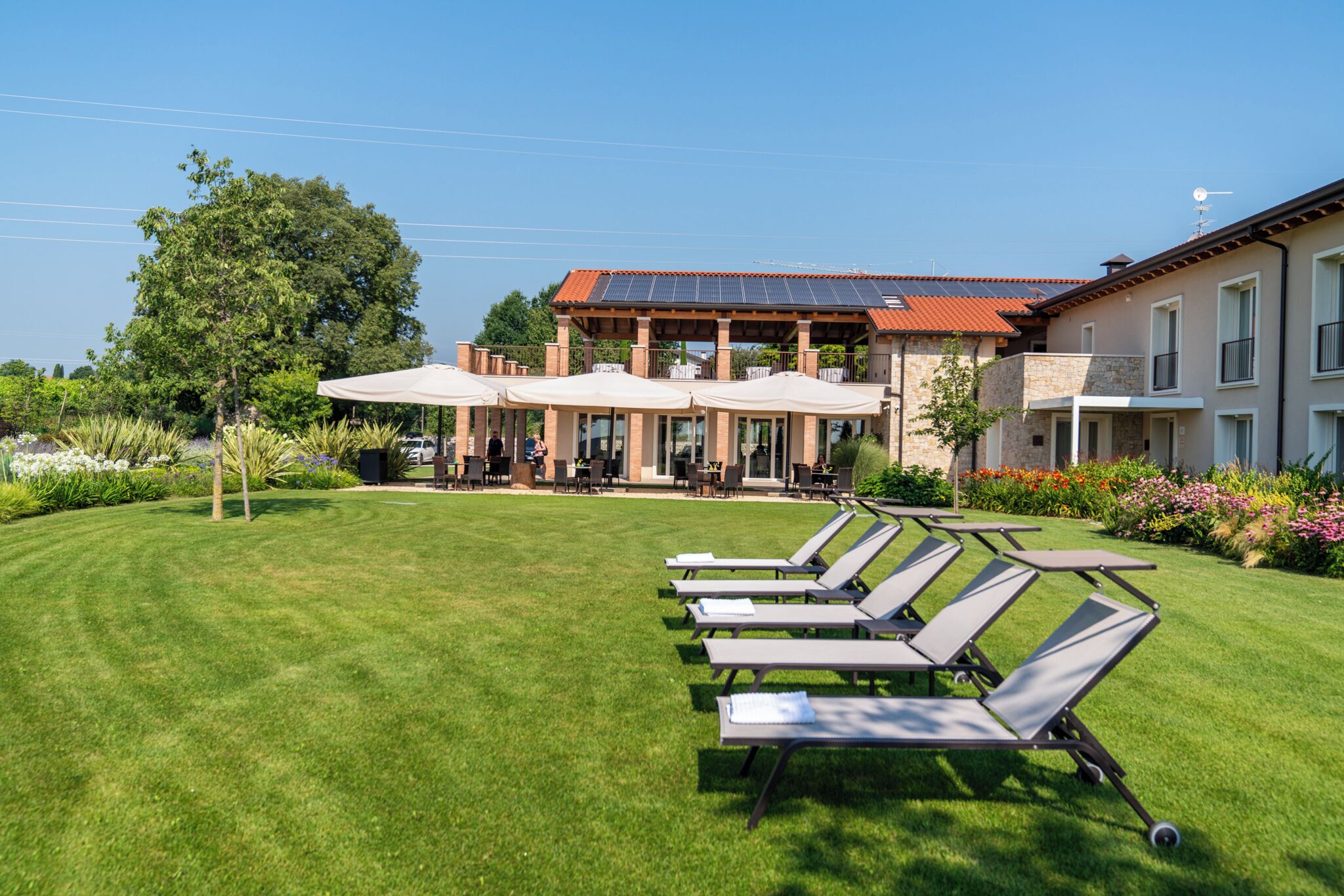 Ein Hotel mit gepflegtem Rasen, einer Sitzgelegenheit im Freien und einem Gebäude mit rotem Dach.