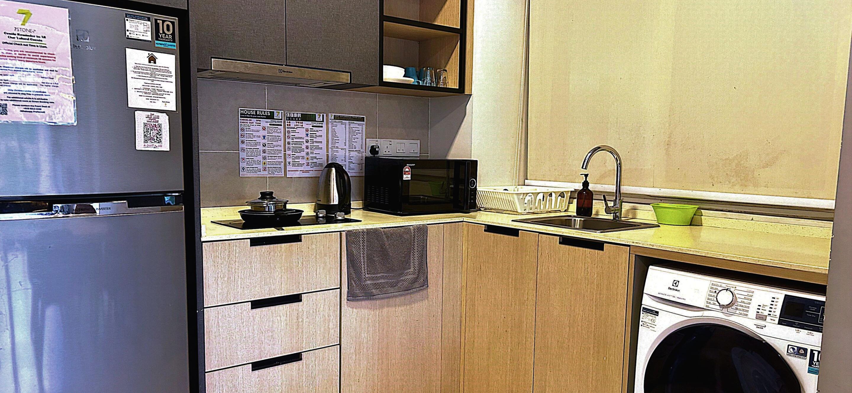 Cocina compacta equipada con refrigerador, microondas, pileta y lavadora.