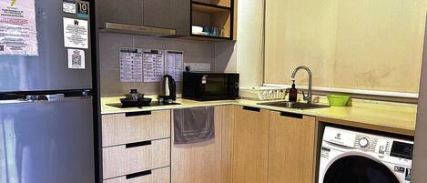Cocina compacta equipada con refrigerador, microondas, pileta y lavadora.