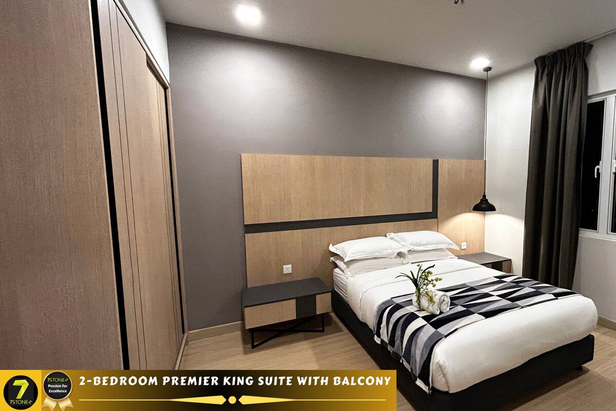 A 2-bedroom premier king suite with a balcony, featuring a modern design with a large bed, bedside tables, and a nightstand.