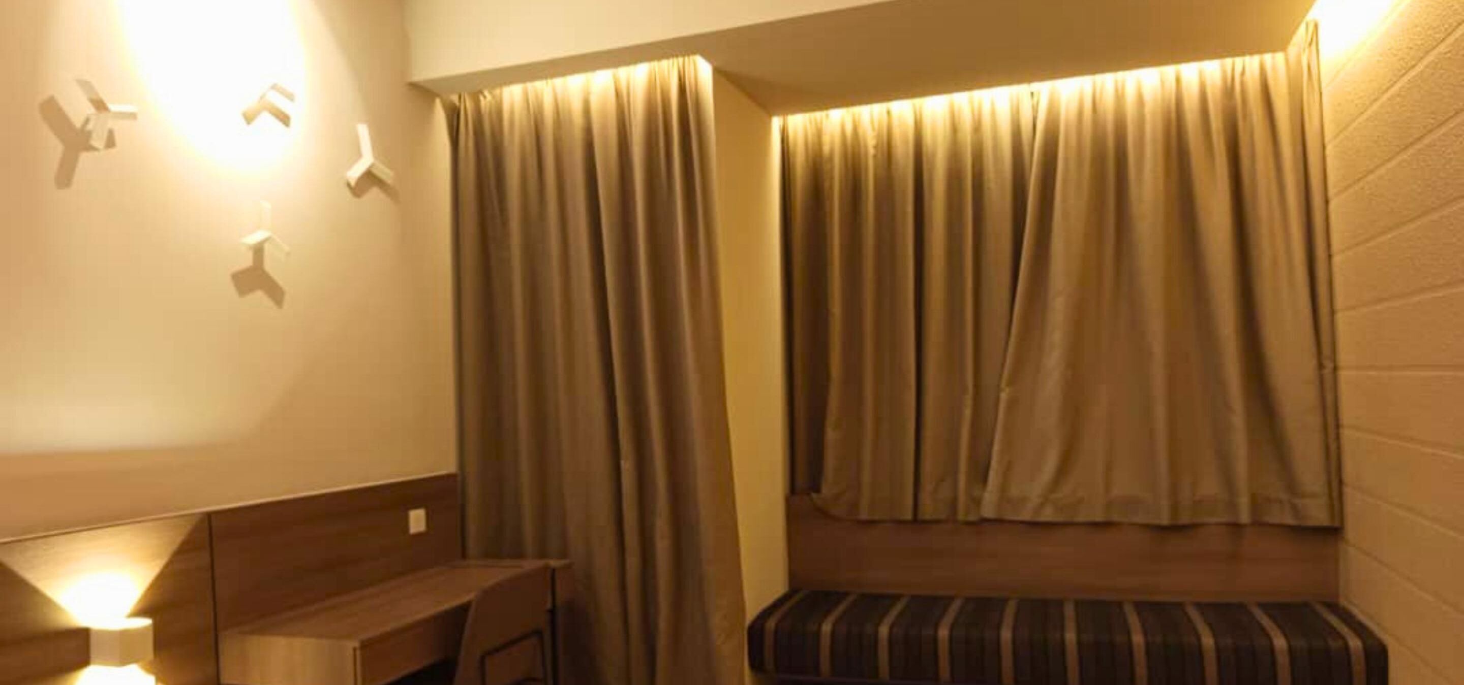 A room with a bed, a bench, and a wall-mounted light fixture.