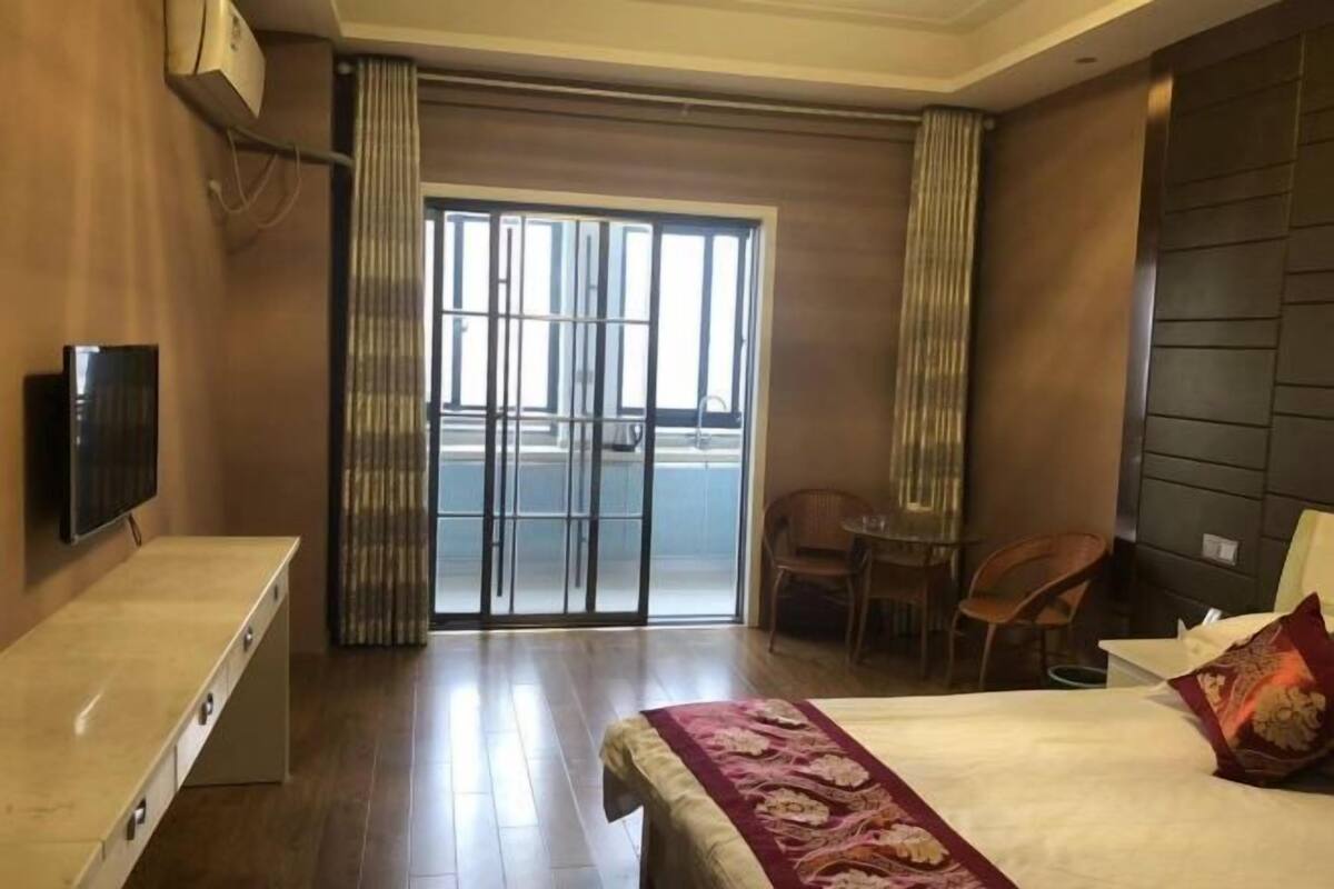 Quarto de hotel com cama, televisão, escrivaninha, cadeira e varanda com vista.