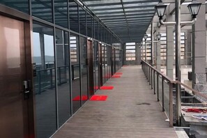 A corridor with glass doors, red mats, and a metal railing. - Shuya Business Hotel (Chizhou)