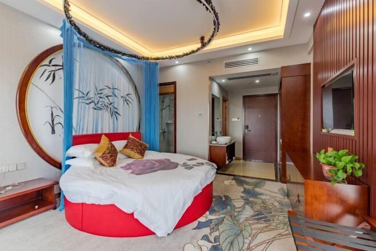 Quarto moderno com cama vermelha, um espelho grande e um guarda-roupa de madeira.
