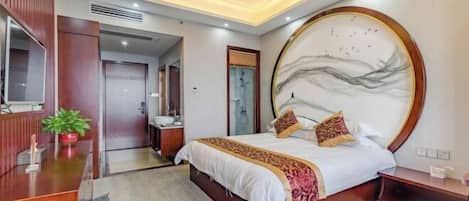 A modern bedroom with a large bed, a TV, a wooden dresser, and a round wall art piece.