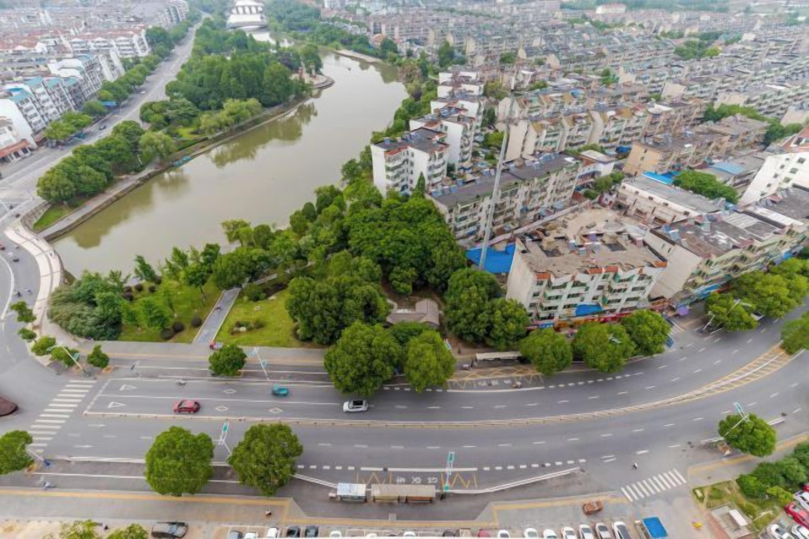 An aerial view of a cityscape with a river, green spaces, and buildings.