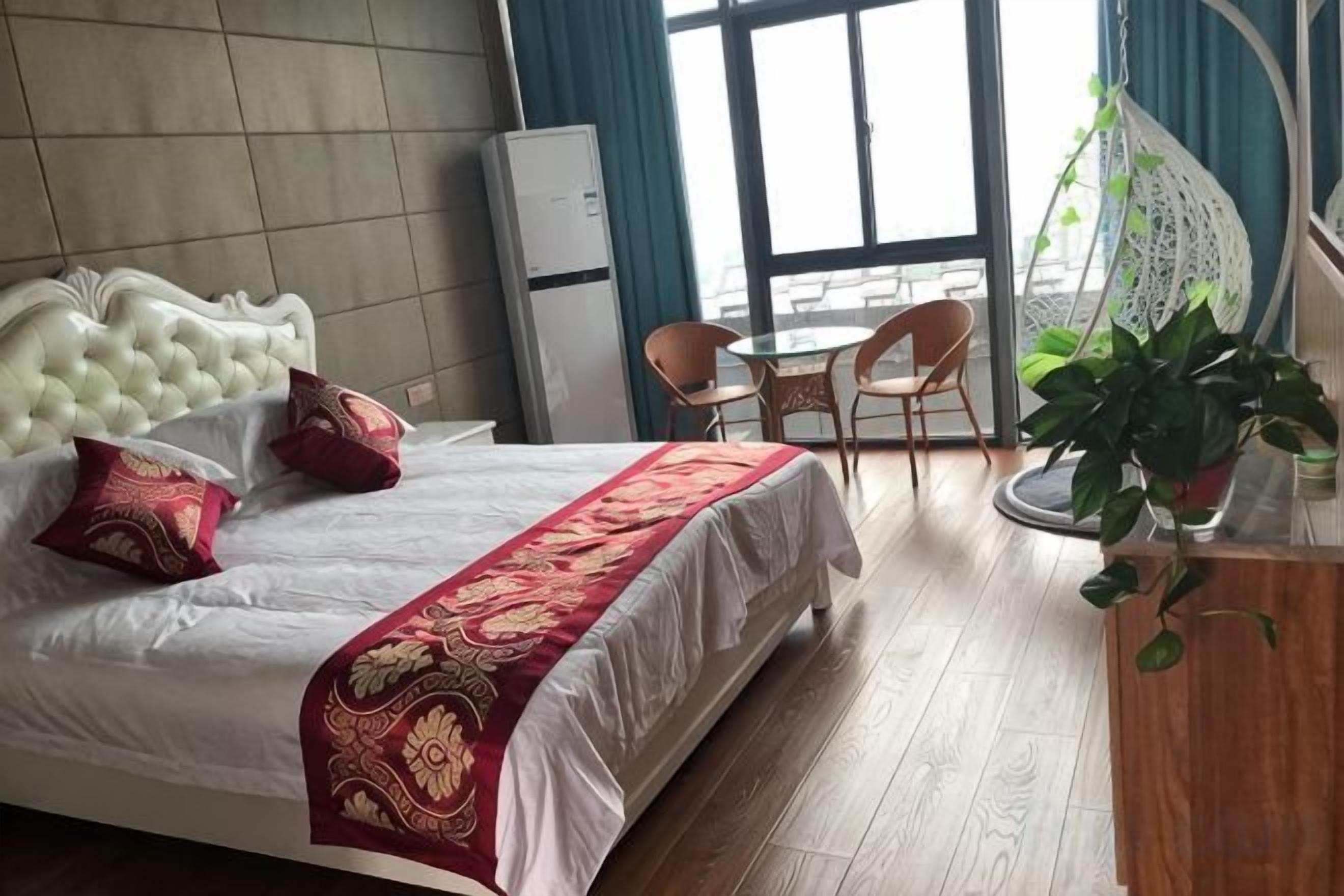 Ett hotellrum med en stor säng, ett skrivbord, en stol, en krukväxt och utsikt över omgivningarna.