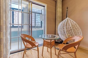 A balcony with wicker chairs, a glass table, and a white hanging chair. - Shuya Business Hotel (Chizhou)