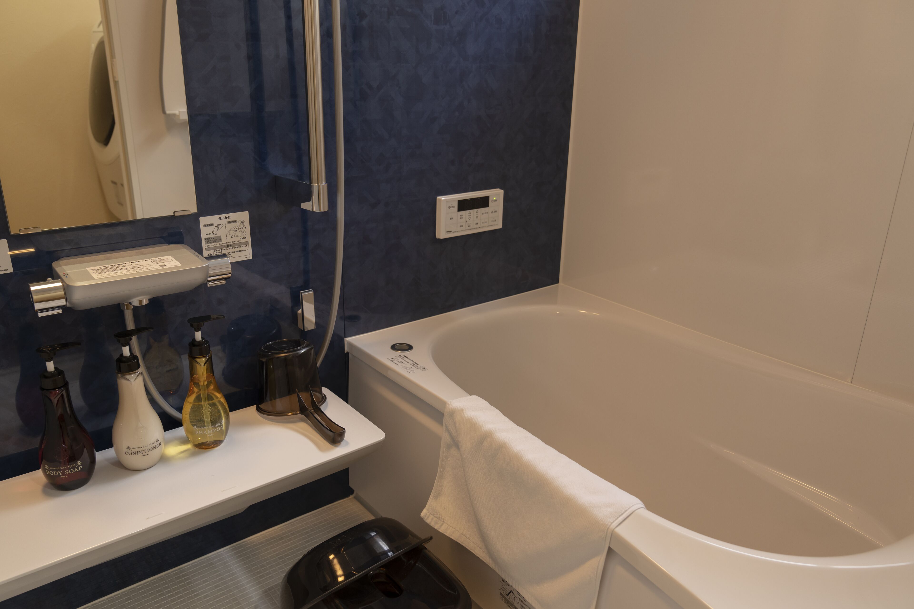 A bathroom with a bathtub, a mirror, a towel rack, and toiletries on a counter.