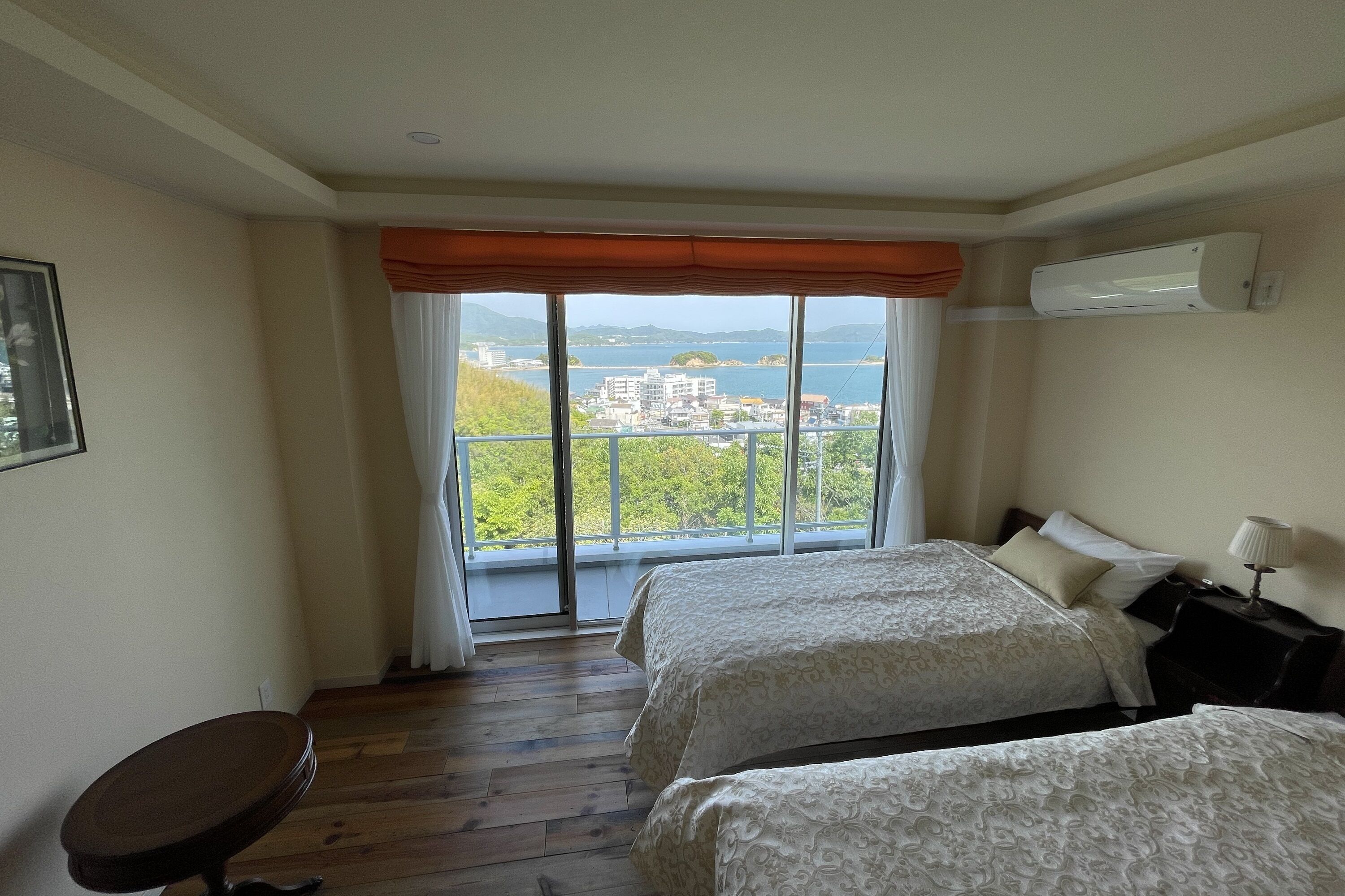 Habitación de hotel con dos camas, vistas al mar y un balcón.