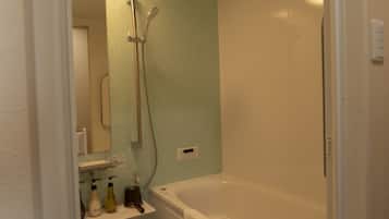 Une salle de bain avec une baignoire, une douche et un miroir.