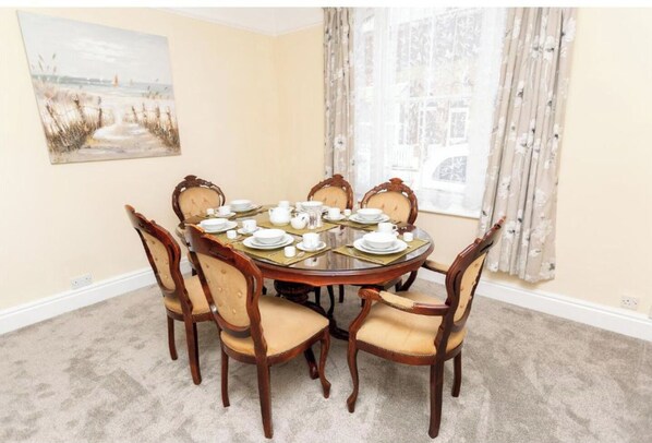 A dining room with a round table set for four, surrounded by four upholstered chairs.