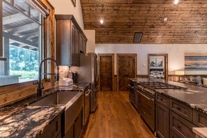 Una cocina moderna con armarios de madera, un refrigerador de acero inoxidable y una isla grande con un lavamanos.