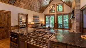 Una cocina amplia con una isla grande, vigas de techo de madera y una chimenea de piedra.
