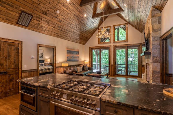 Una cocina amplia con una isla grande, vigas de techo de madera y una chimenea de piedra.