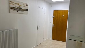 A hallway with a radiator, a white door, and a wooden door.