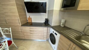 A compact kitchen with a built-in washer, a microwave, and a sink.