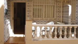 A balcony with a white balustrade, patterned tiles, and a window with bars. - Apartamento de 1 Dormitorio Cerca de la Playa (Fuengirola)