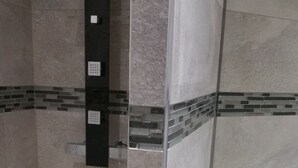 Un bagno moderno con cabina doccia in vetro, lavabo bianco e pareti piastrellate.