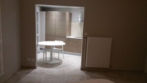 Una cucina compatta con un tavolo e sedie bianche, forno a incasso e termosifone.