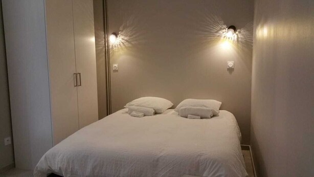 Un dormitorio con cama, dos luces fijadas a la pared y un armario.