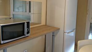 Una cocina compacta con microondas, refrigerador y encimera de madera.