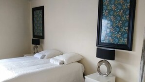 Una habitación de hotel con una cama, un escritorio y dos cuadros en la pared.