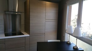 Una cocina moderna con estufa integrada, armarios de madera y ventana con vistas a la ciudad.