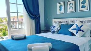 A bedroom with a bed, blue and white bedding, starfish pillows, and framed artwork on the wall. - Zarbalı Cunda (Ayvalik)