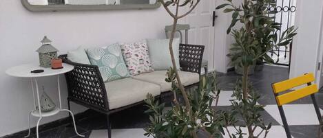 A living room with a sofa, chairs, a small table, and a potted plant.
