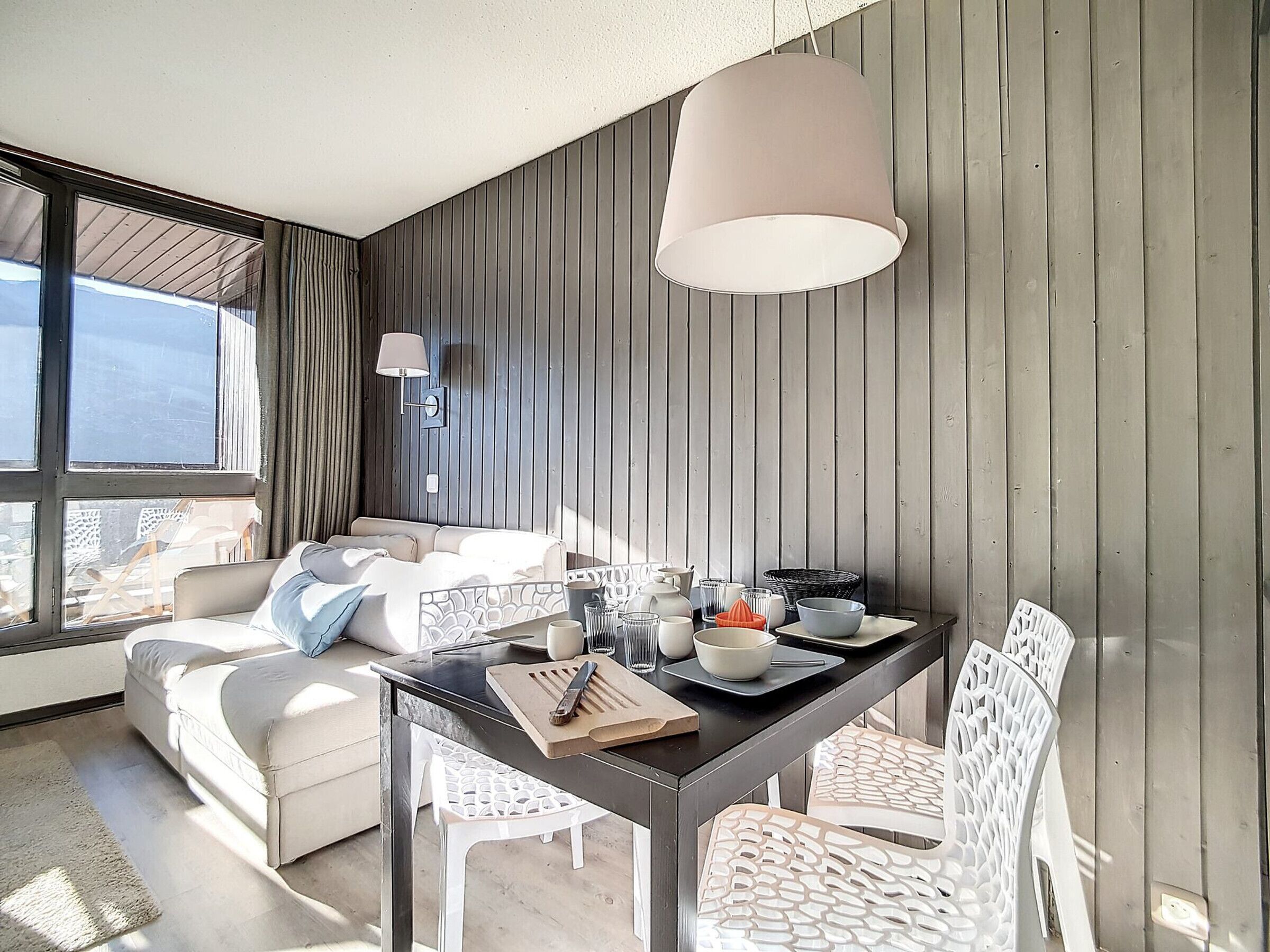 Ein modernes Hotelzimmer mit Essbereich, einer Couch und Blick durch große Fenster.