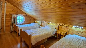 A cozy attic bedroom with wooden walls and sloped ceilings, featuring two beds and a small table. - Spacious Duplex 3BR - Sleeps 6/8 - Balcony (Flaine)
