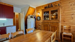 A wooden interior with a dining table, chairs, a refrigerator, and a kitchen area with cabinets and a microwave. - Spacious Duplex 3BR - Sleeps 6/8 - Balcony (Flaine)
