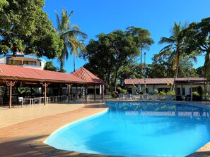 A pool area with lounge chairs and a covered seating area.