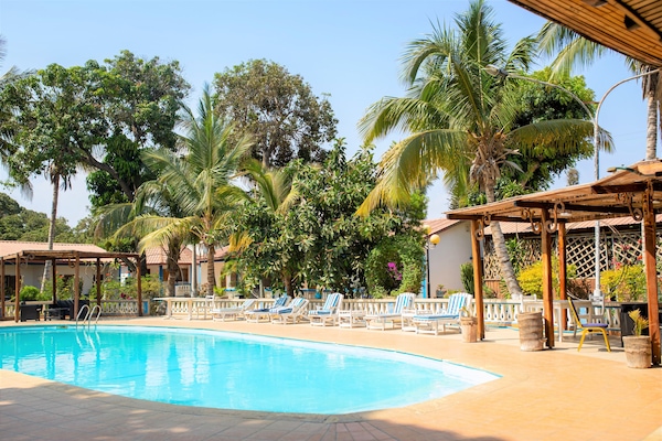 Una piscina al aire libre, sombrillas, sillones reclinables de piscina