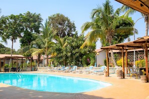 Una piscina con sillas de descanso y palmeras.