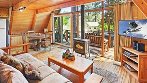 A cozy cabin interior with a dining area, a fireplace, a sofa, and a television.