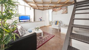 A modern living room with a TV, a sofa, a coffee table, and a staircase. - Inviting 3-bed Apartment in Roma 4mins to Colosseo (Rome)