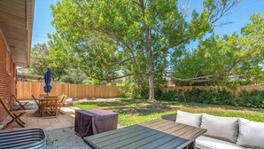 A backyard with a wooden deck, outdoor furniture, and a large tree. - Peaceful home with fire pit and game room (Denver)