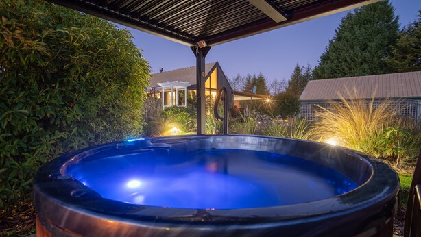 Un bain à remous dans un jardin, avec une maison en arrière-plan.