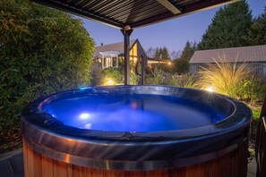 Un bain à remous dans un jardin, avec une maison en arrière-plan.